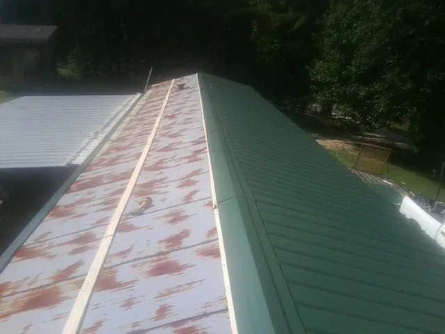Old rusted panels beside newly installed green metal roofing — Wind Damage Roof Repair by Roofing Brothers in Merry Hill