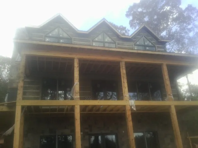 Dormers and porch framing on a large log home under construction — Roof Coating work by our crew in Merry Hill