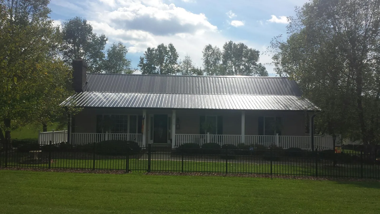 Gray metal roof on a brick ranch with a full width front porch — Gutter Guard Installation work by our crew in Merry Hill