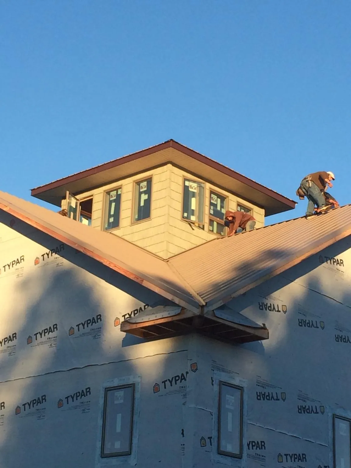 Roofers working around a rooftop cupola on a new metal roof at sunset — Roof Waterproofing in Merry Hill by Roofing Brothers